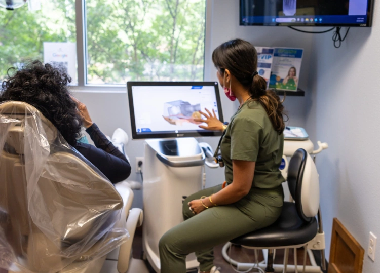 Dental hygienist consulting with patient in modern orthodontic office treatment room.